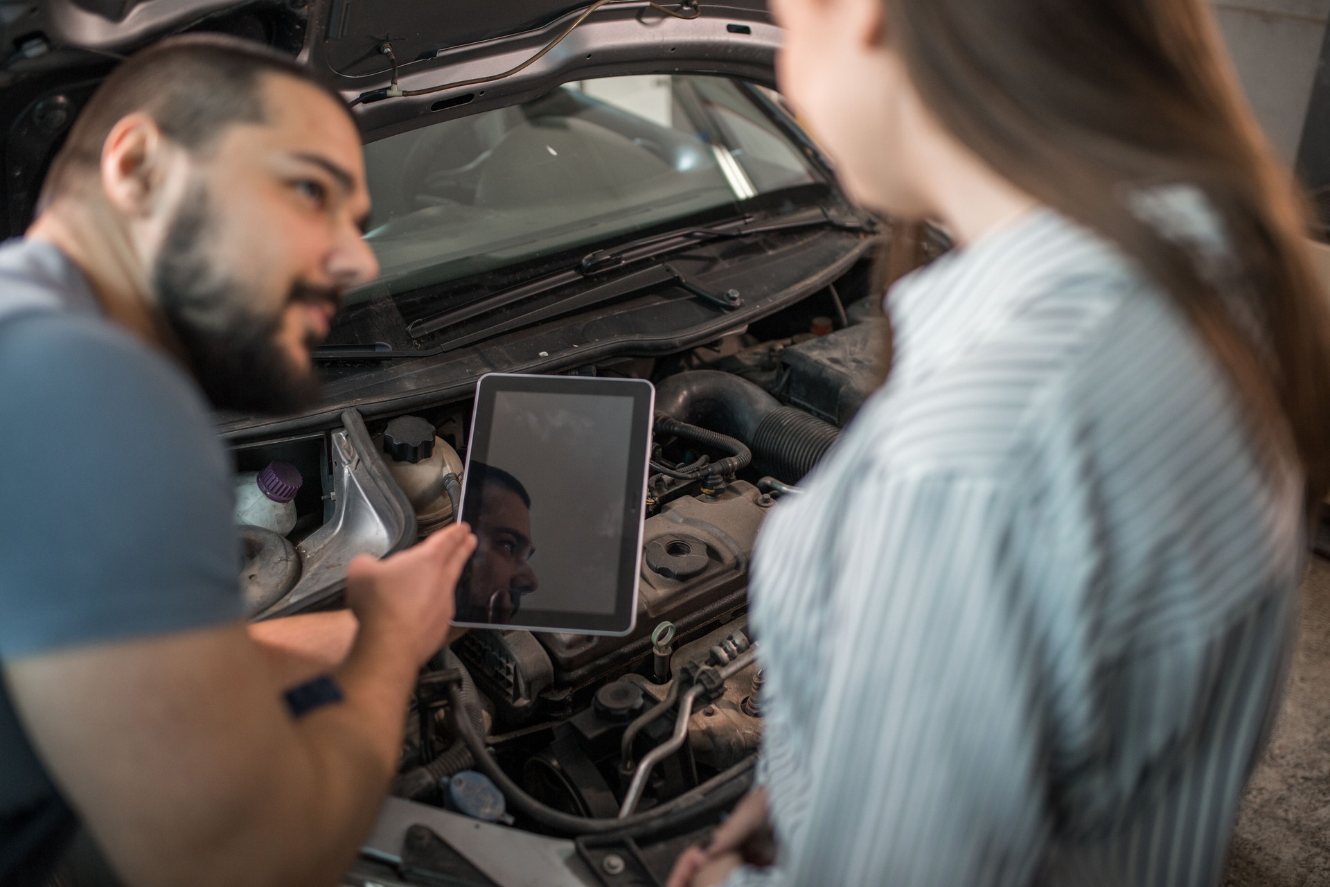 Mecánico de coches usando tableta en taller de reparación de autos